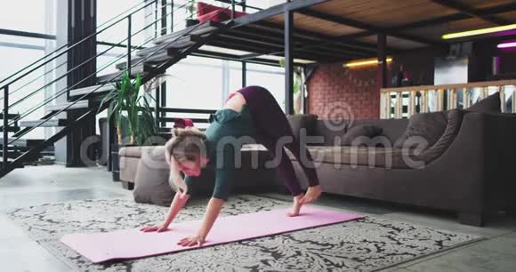 女士早上在家里练习瑜伽她在令人惊叹的阁楼上做身体伸展运动叫向下面对狗视频的预览图