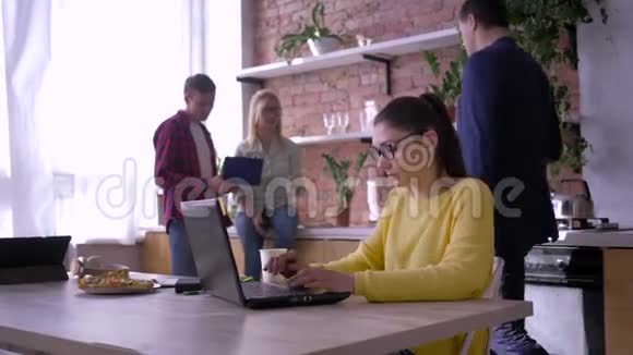 现代办公室女商人戴着眼镜在笔记本电脑上工作而合作者则吃三明治并在视频的预览图