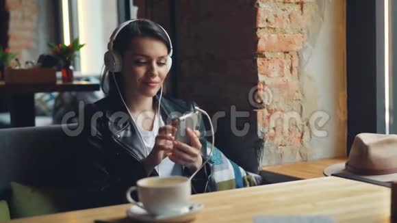 快乐女学生在咖啡馆里用智能手机用耳机听音乐视频的预览图