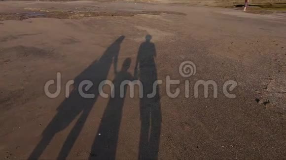 在岩石海岸上一家人手牵着手走着一幅家庭的剪影视频的预览图