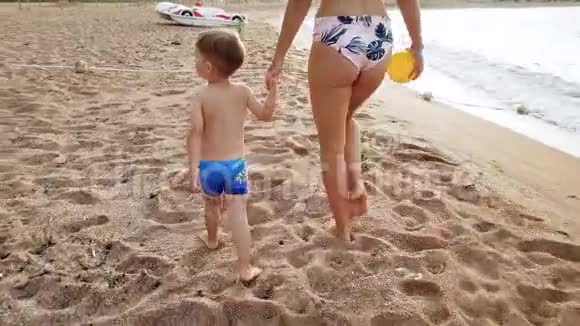 4k视频美丽的年轻女子与她的3岁孩子男孩在海滩上散步日落视频的预览图