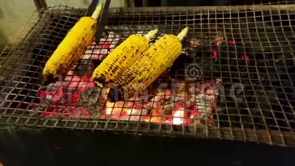 玉米棒上烤玉米木炭烧烤上烤三个甜玉米烤肉酱上烤玉米玉米棒上烤视频的预览图