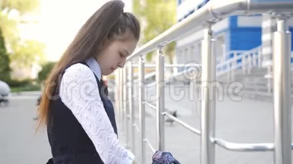 悲伤的高中女孩放学回家小女孩把背包扔在他的肩膀上然后走回家视频的预览图