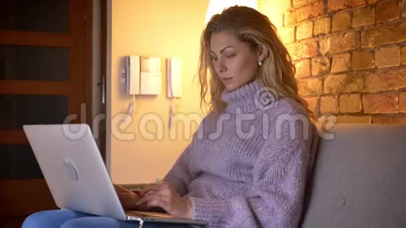 特写侧景拍摄成年白种人迷人的女性在笔记本电脑上打字坐在电脑上开心地微笑视频的预览图