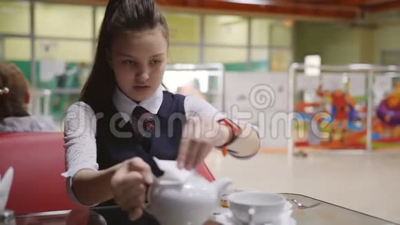 在学校食堂休息一个十几岁的女孩把茶从水壶里倒入杯里视频的预览图
