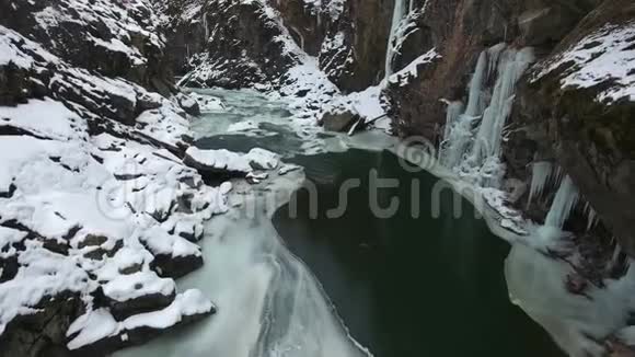 峡谷底部冻结河流岩石上有冰柱视频的预览图