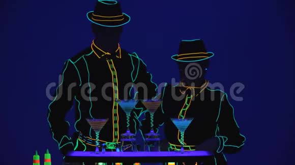 巴门表演业绩酒吧招待和酒吧招待提供美味的鸡尾酒明亮的蓝色背景慢动作4K视频的预览图