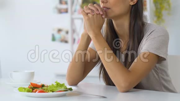 年轻女子在吃饭前祈祷请求上帝保佑食物信仰基督教视频的预览图