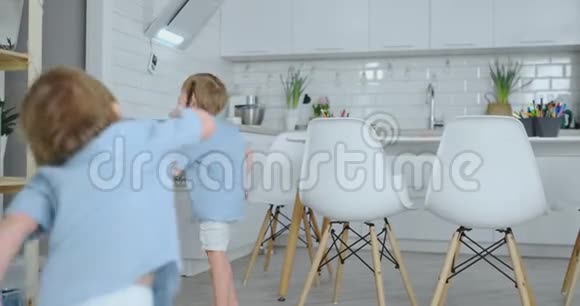 两个孩子跳起来喜欢在厨房的房子里跑步视频的预览图