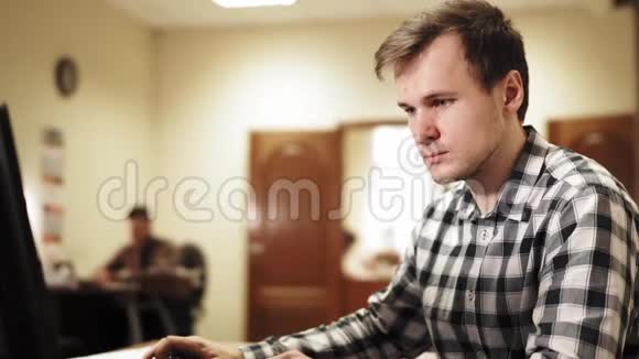 年轻人坐在办公室里在电脑上工作说话视频的预览图