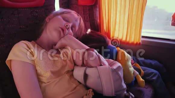 两个疲惫的小女孩睡在旅游巴士的背包上视频的预览图