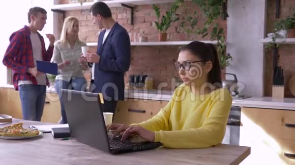日常办公室工作女商人戴着眼镜在笔记本电脑上工作而同事则吃快餐在此期间进行交流视频的预览图