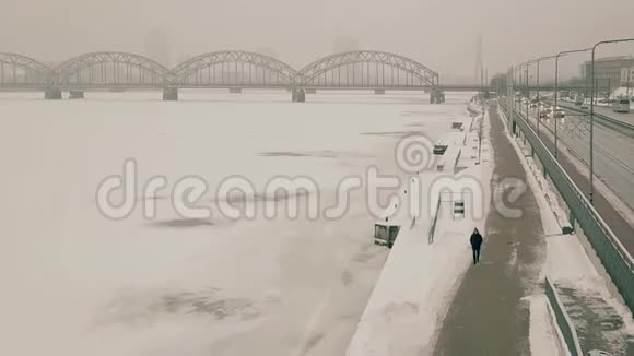 男人在冬天的河边散步拍摄于一架无人机在它前面移动1080p25fps视频的预览图
