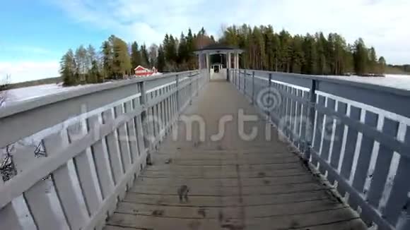 在欧洲一个冬天的仙境里骑自行车骑在白色的木桥上周围是桦树松树视频的预览图