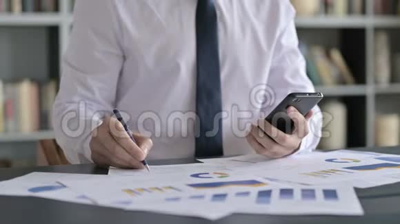 商务人士用手机处理文件的特写镜头视频的预览图