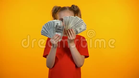 令人惊讶的可爱女孩拿着一束美元现金第一收入银行业务视频的预览图