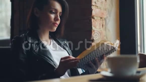 漂亮的女学生在咖啡馆里看书独自坐在桌子上放松视频的预览图