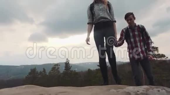 年轻的徒步旅行者在岩石山上游荡时髦的一对爱冒险情侣目标神奇的自然高山视频的预览图