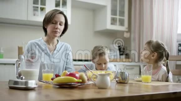 母亲在早餐时与孩子交流给孩子加牛奶玉米片碗视频的预览图
