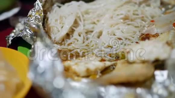 在亚洲街头食品市场游客吃米粉和用箔纸煮熟的鱼关门视频的预览图
