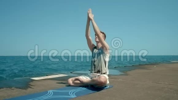 坐在海边的人坐在莲花的位置然后站在他的头上做瑜伽的男人视频的预览图