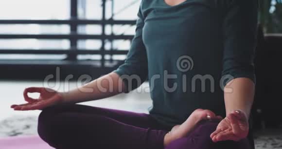 瑜伽冥想的细节在家里的女人为自己练习在一个现代的顶层公寓她坐下来视频的预览图