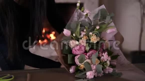 布吕内特女士穿着休闲花艺花店包花粉红色玫瑰在礼品纸在车间家庭工作室视频的预览图