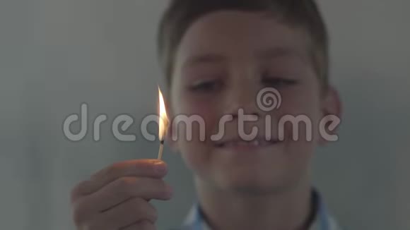 小男孩在黑暗的烟雾弥漫的房间里玩火柴的特写肖像孩子笑着点燃火柴这就是视频的预览图