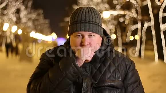 冰冻男子在寒冷的冬夜在户外咳嗽的肖像视频的预览图