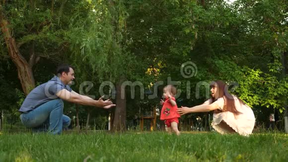 春天夏天小女儿在公园里的绿草上从妈妈到爸爸幸福的家庭观念孩子是第一个视频的预览图