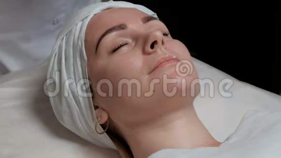 一个美丽的女孩在美容院的肖像美容师治疗师擦拭客户的脸这就是视频的预览图