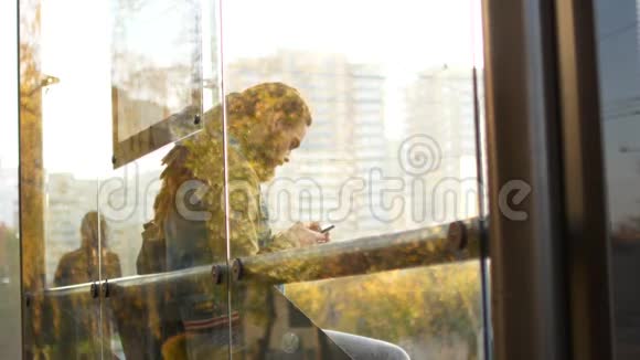 一个人在公共汽车站等公共汽车一个人在等待交通时使用移动互联网视频的预览图