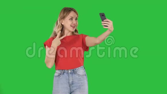 快乐的女人30岁穿着红色T恤在绿色屏幕上行走时自拍照片Chroma键视频的预览图
