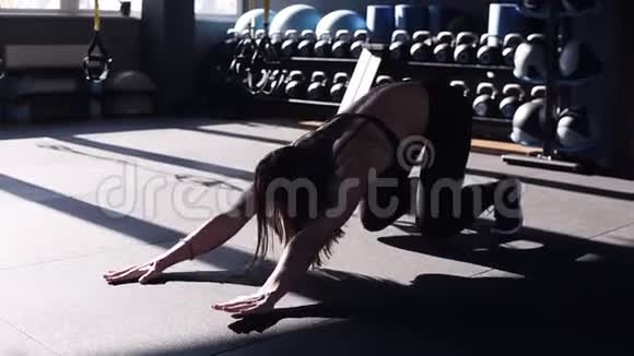 漂亮的年轻健美女士穿着黑色运动胸罩和紧身裤在健身房地板上做运动伸展运动视频的预览图