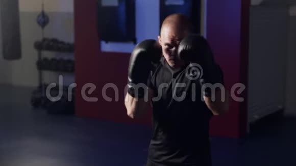 拳击手带着拳击手套在健身房的摄像机上打拳打影子慢动作视频的预览图