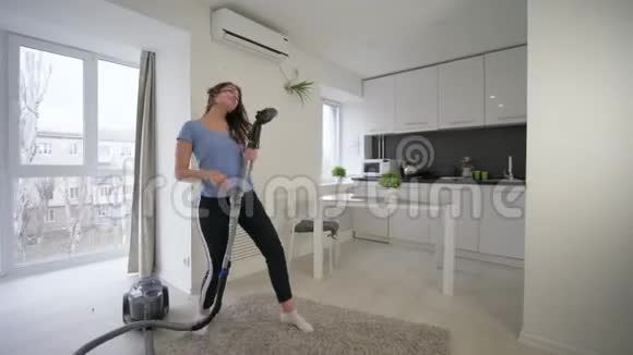 开朗的家庭主妇做清洁真空在家里的房间里跳舞唱歌玩得开心视频的预览图