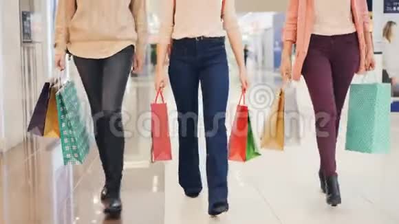 低镜头的女士腿走在购物中心与纸袋享受购买衣服和礼物青年视频的预览图
