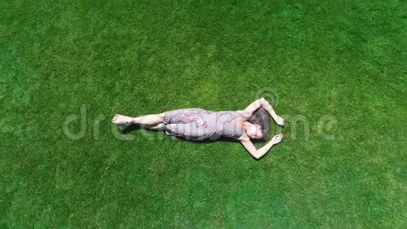鸟瞰女人躺在绿草上享受生活感受快乐无忧无虑的夏天视频的预览图