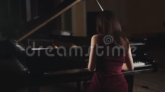 女钢琴家在黑暗中弹钢琴从后面射击视频的预览图