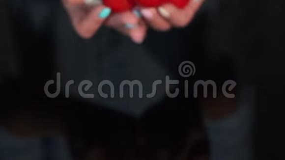 红色的西红柿在女人手中水滴在黑色的背景上视频的预览图