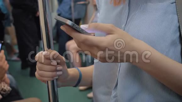 女士双手使用智能手机应用程序站在地铁汽车与许多乘客视频的预览图