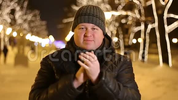 冬天寒冷的夜晚快乐的男人在户外拍手的肖像视频的预览图