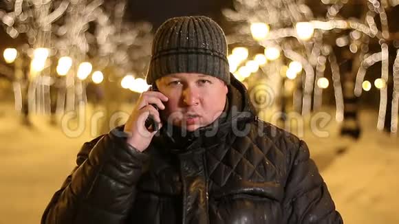 一个冬天的帅哥在一个寒冷的夜晚在一条城市街道上打电话视频的预览图