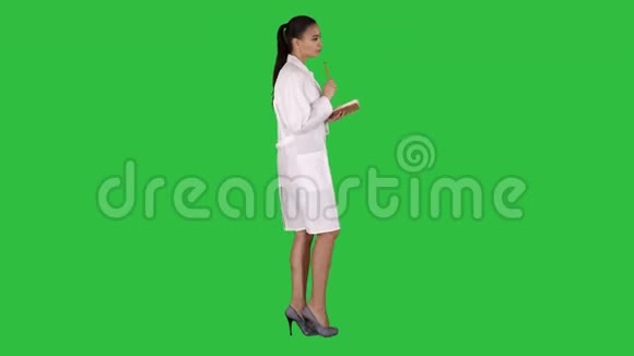 成功的医生一边做笔记一边走在绿色屏幕上彩色键视频的预览图