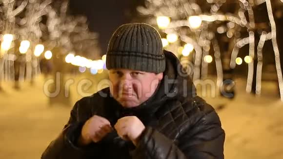 愤怒的大个子站在拳击手的姿势下准备在寒冷的冬夜在户外战斗的画像视频的预览图