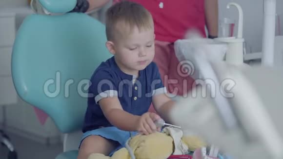 可爱的小男孩坐在牙医办公室的椅子上玩医疗工具免费儿童探访视频的预览图
