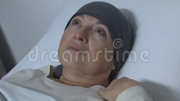 戴着围巾的沮丧女士躺在床上没有康复的希望癌症治疗视频的预览图