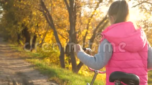 女孩在路上骑自行车秋天在公园里散步视频的预览图