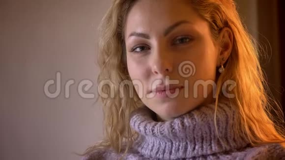 在一间舒适的公寓里一位成年白种人漂亮的金发女性看着摄像机带着诱人的微笑特写视频的预览图