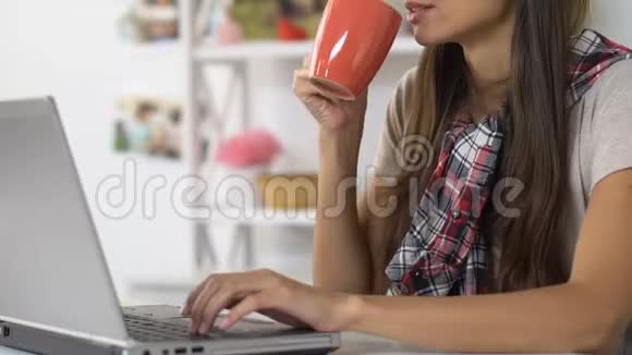 在笔记本电脑和家里喝咖啡的女孩女记者自由职业者视频的预览图